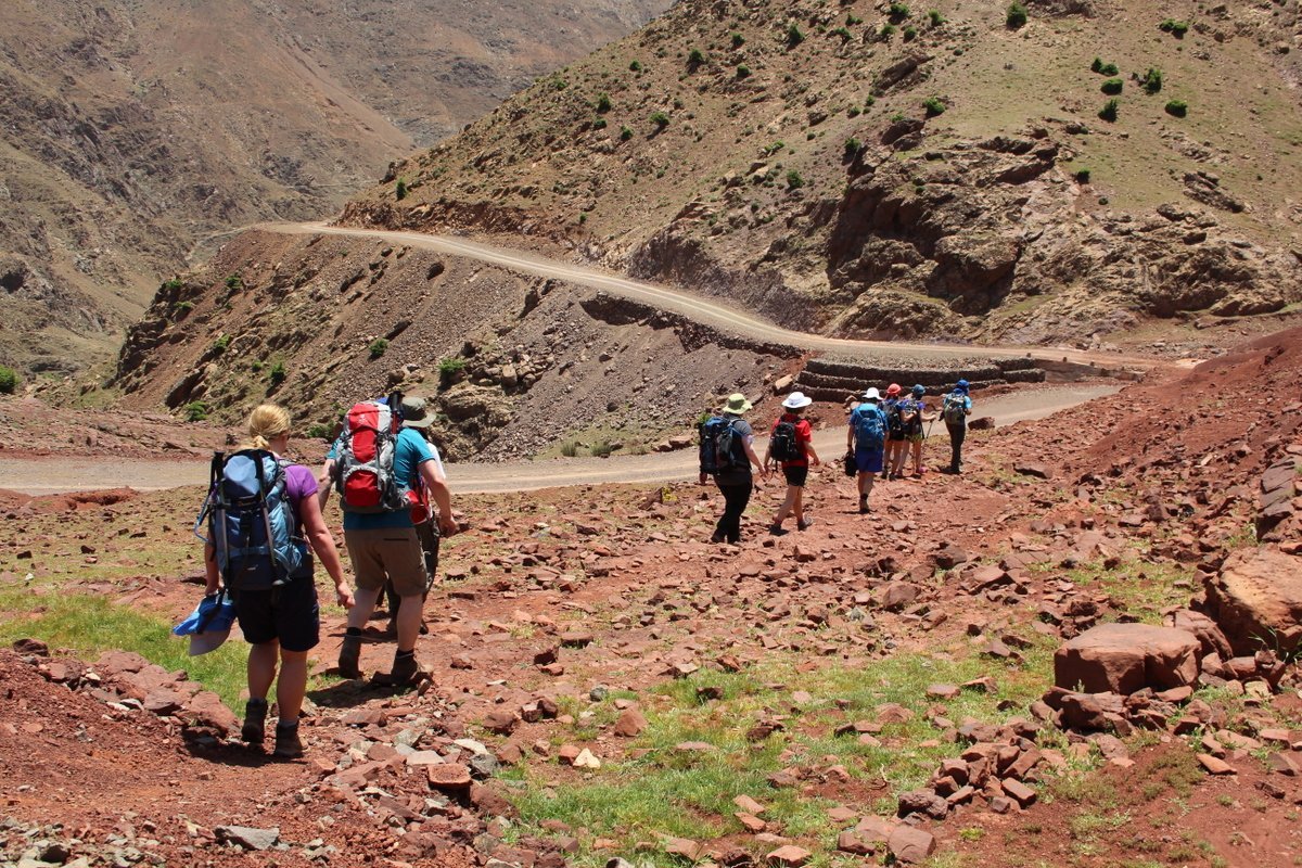 Group of trekkers on a red-earth track through the Atlas foothills