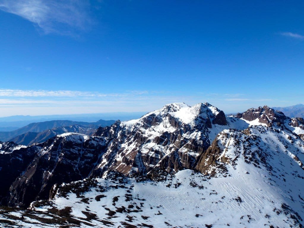 Snow-covered High Atlas peaks under a clear sky, seen from high on the trek