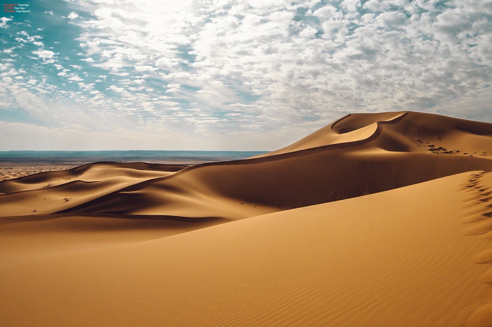 Golden Sahara sand dunes under a clouded sky