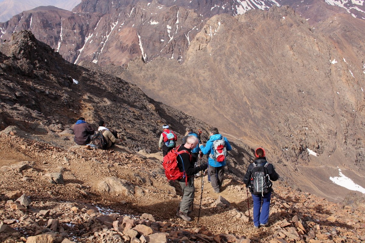 Trekkers with walking poles descending a steep scree slope