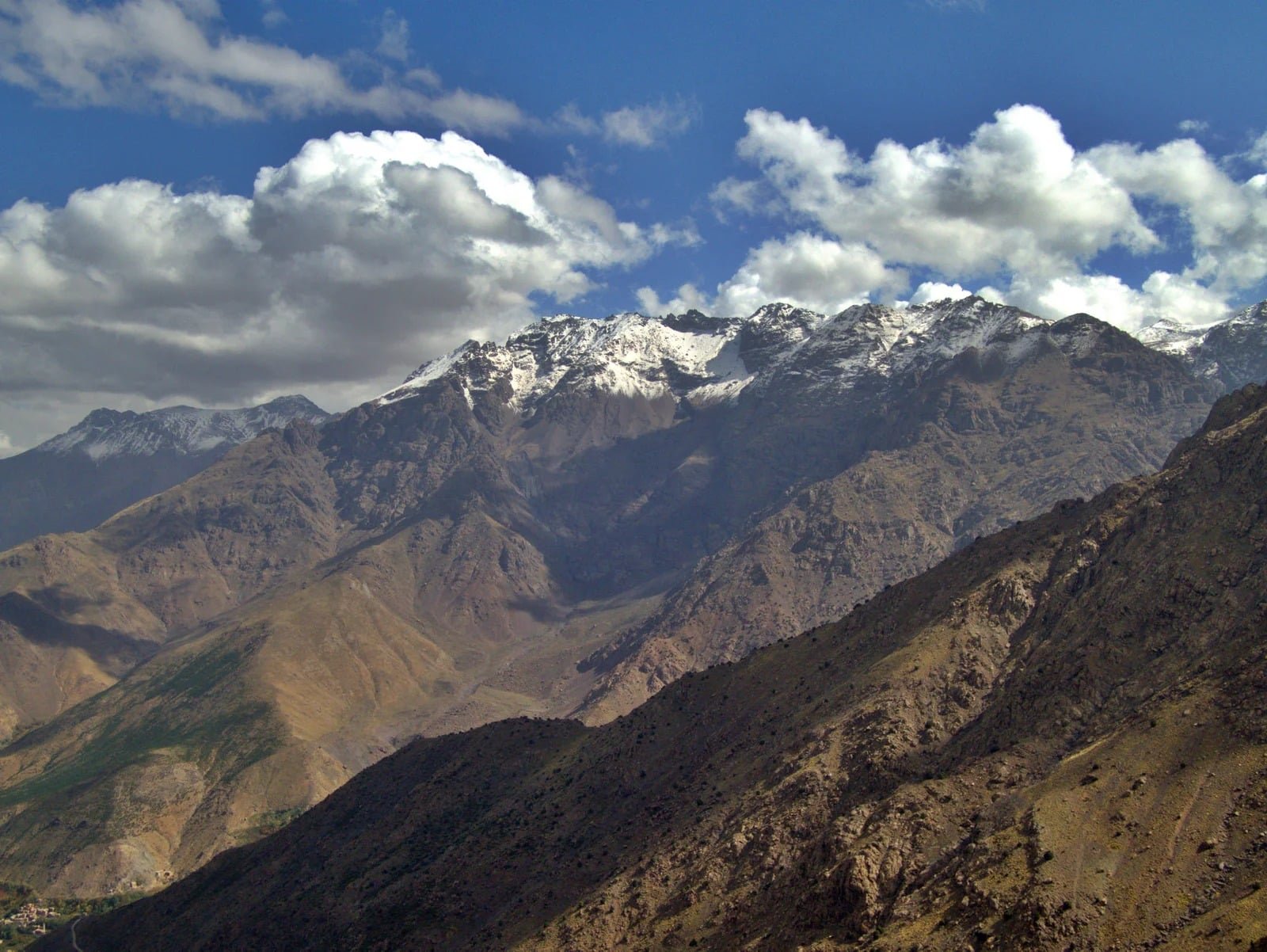 Snow-dusted High Atlas peaks under clouds above brown mountain slopes