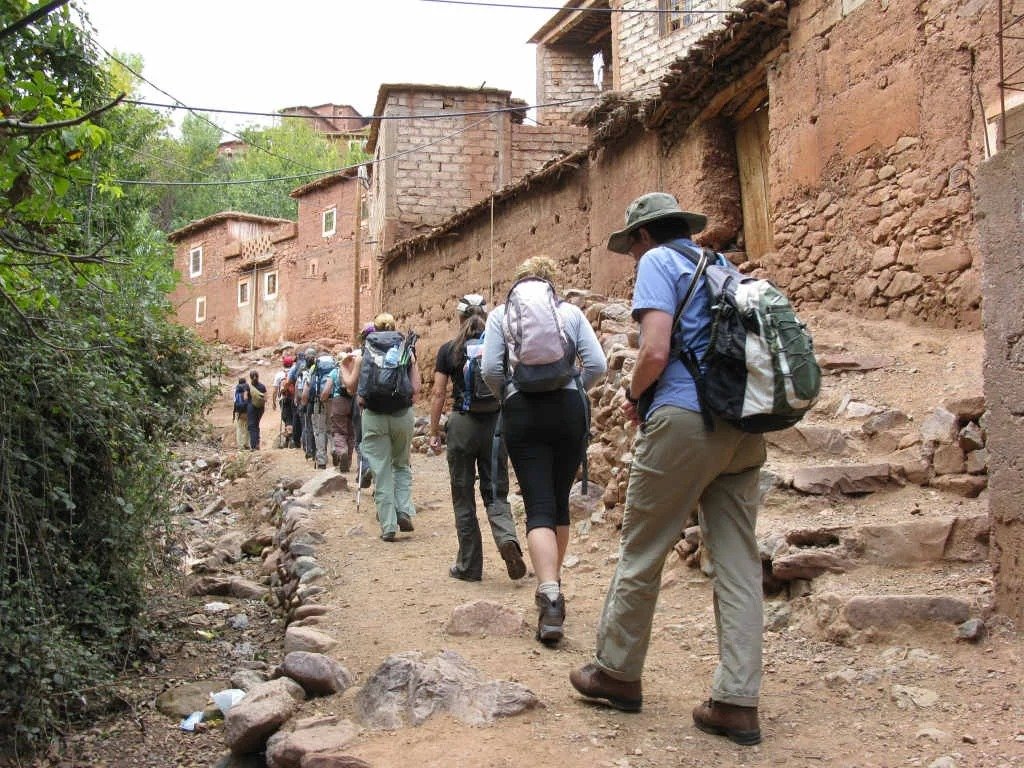 Group of trekkers walking a stone path through a Berber village in the Atlas Mountains