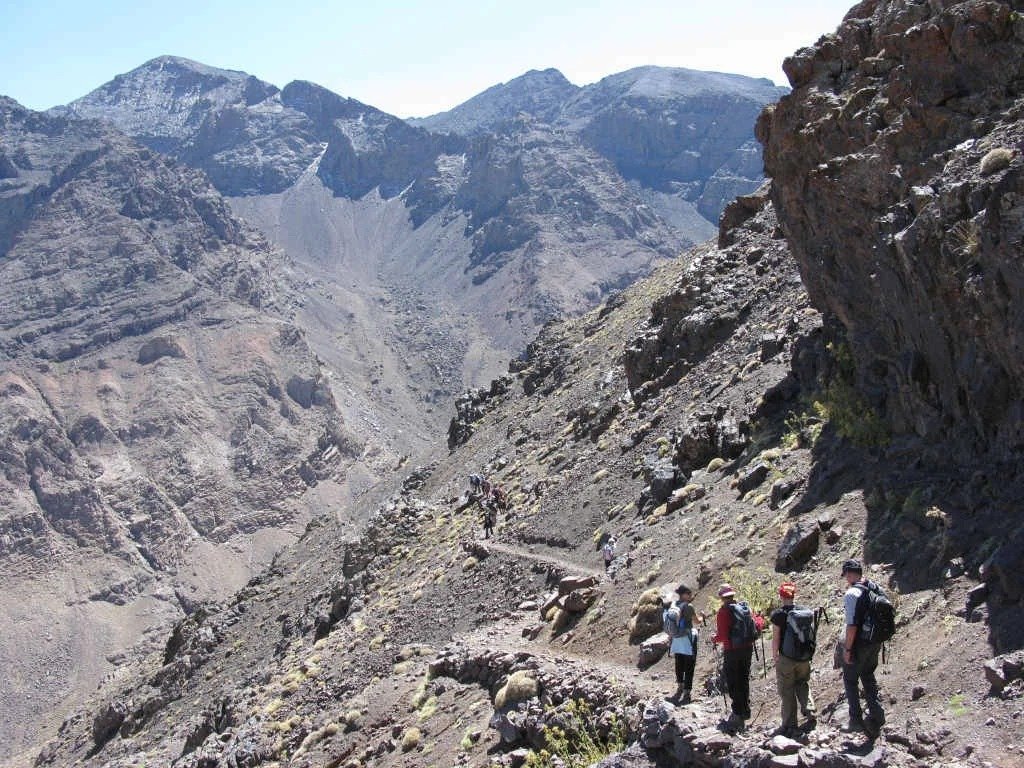 Trekkers on a narrow path along a steep High Atlas mountainside