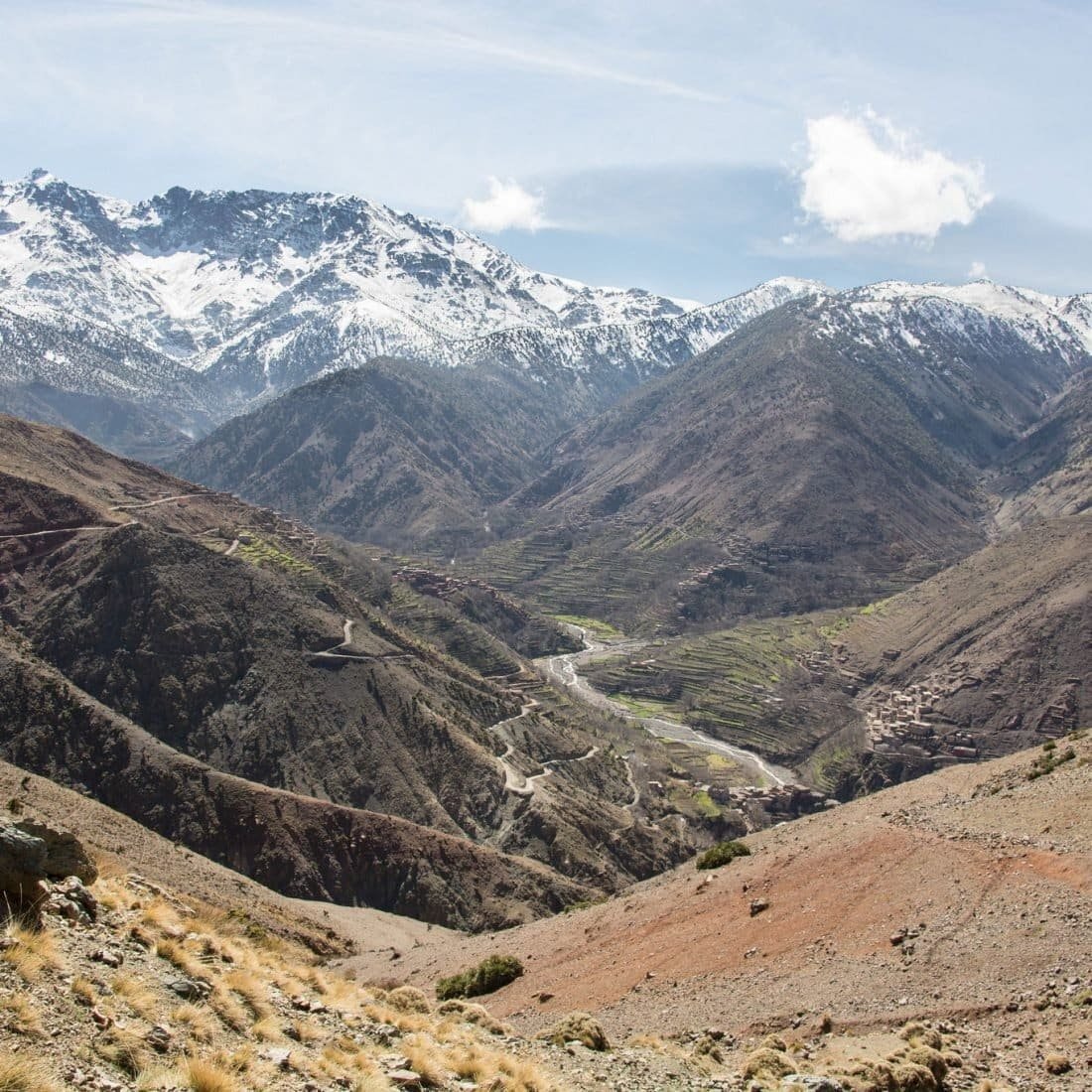 Winding river valley below snowy High Atlas peaks