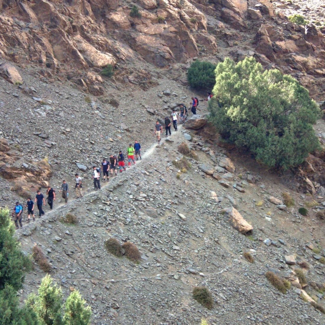 Long line of trekkers on a stony mountain path in the Atlas