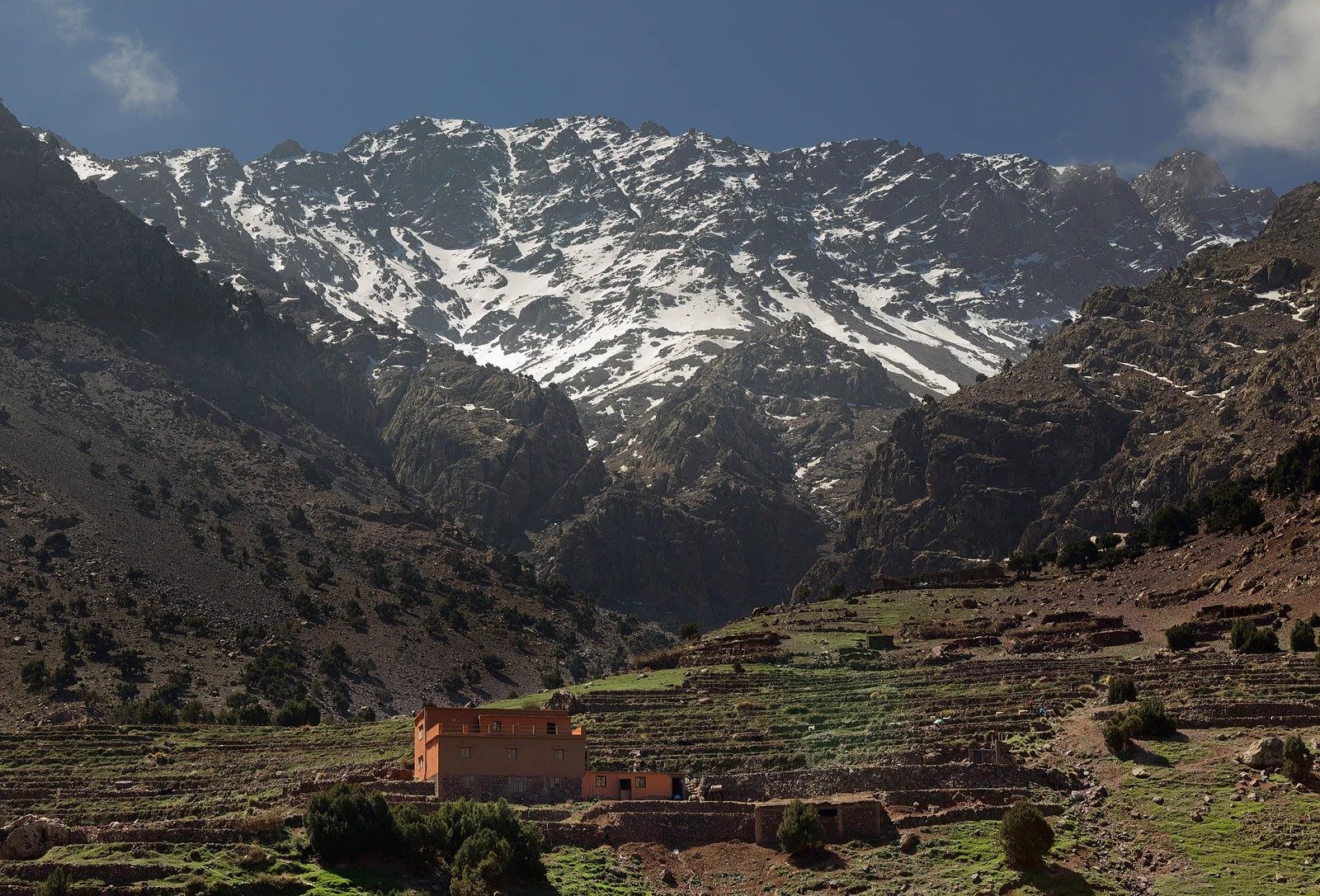 Snow-streaked High Atlas ridge above a small farmhouse and fields