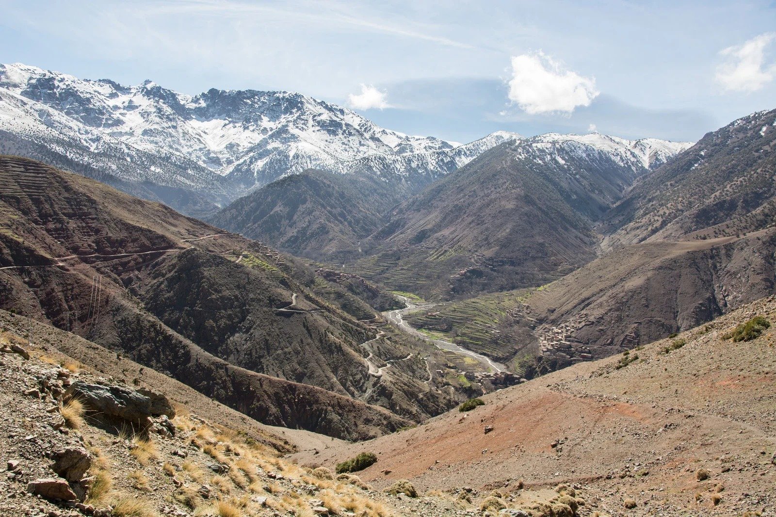View down a winding valley below snow-capped High Atlas peaks