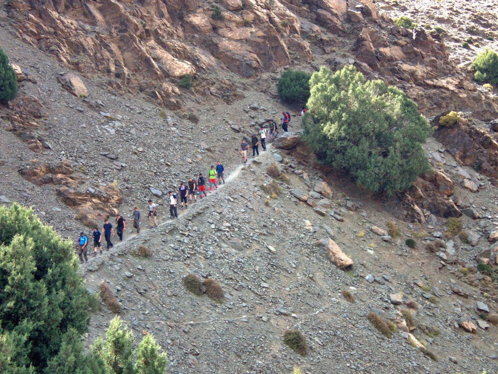 Group of trekkers on a stony path climbing a mountainside
